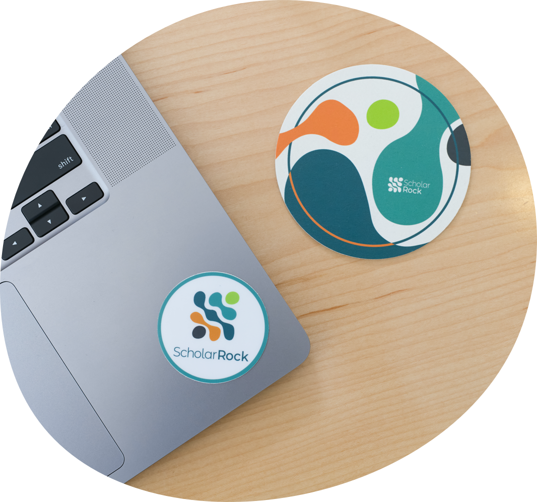 Close up of Scholar Rock branded mouse pad and lap top with Scholar Rock sticker