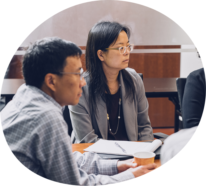 Middle aged asian male and female sitting at a conference table
